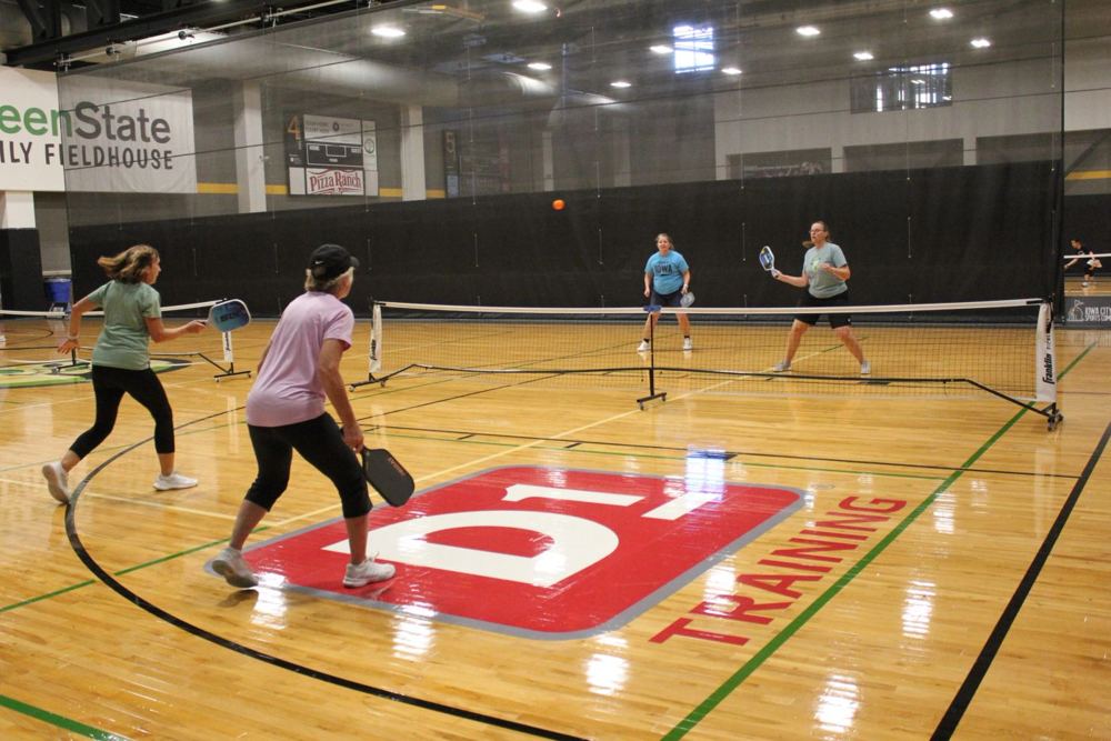 Doubles players mid-rally on an indoor court